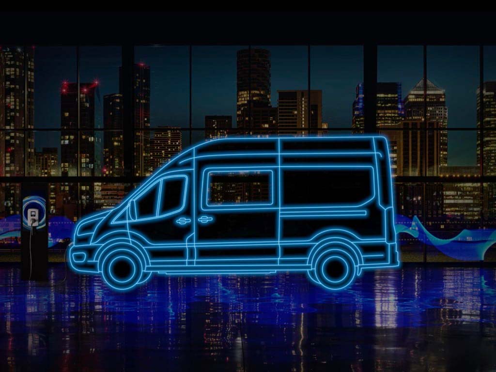 Ford Etransit double cabine en néon parqué dans un immeuble de nuit avec vue sur la ville